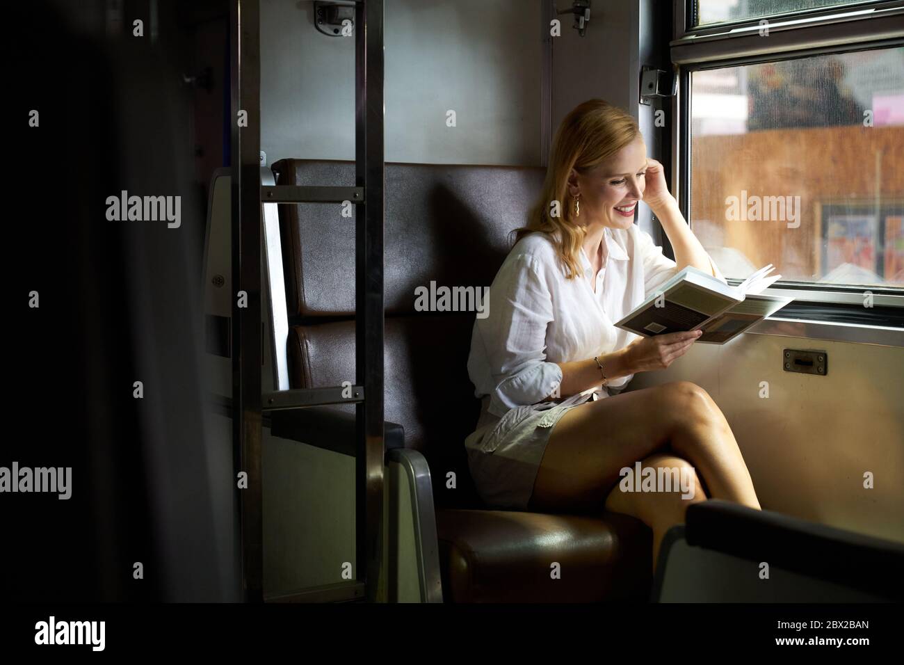 Una donna che legge un libro su un treno Foto Stock