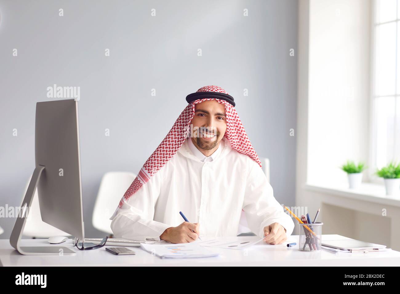 Il calmo uomo arabo siede ad un tavolo nell'ufficio. A. Foto Stock
