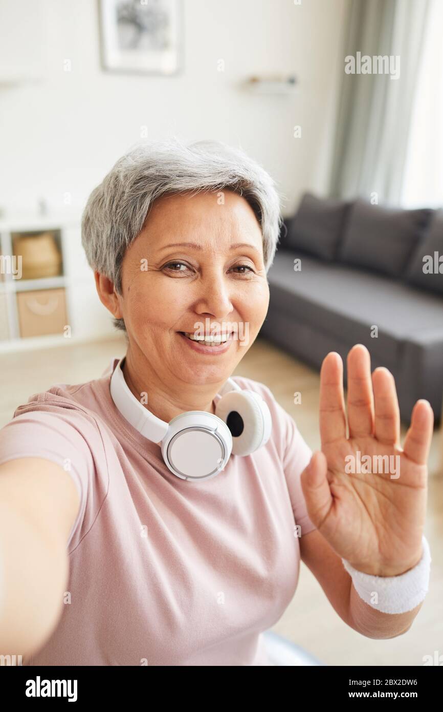 Ritratto di donna anziana sorridente alla macchina fotografica e sventolando la mano dice Ciao Foto Stock