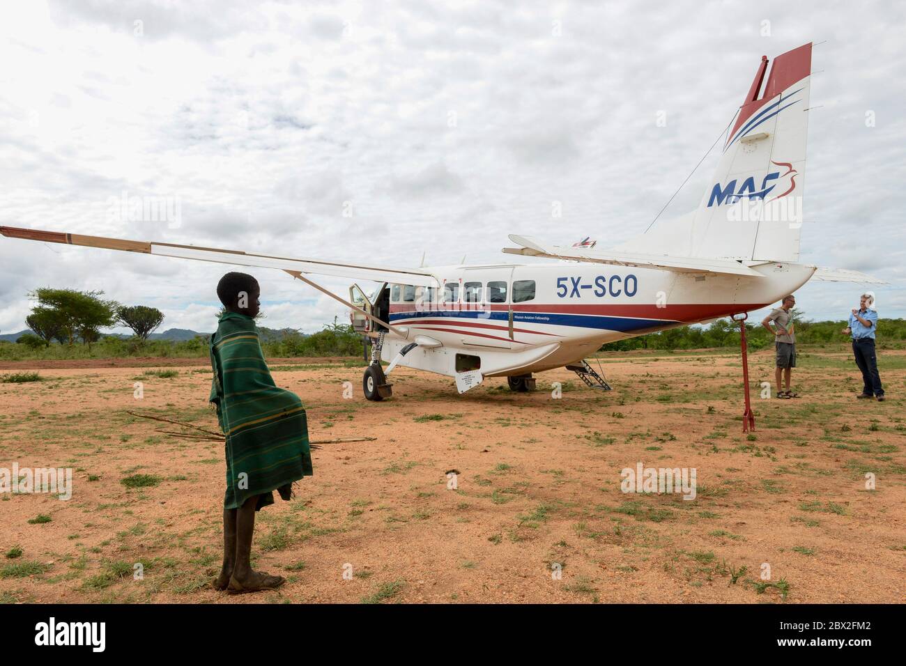 UGANDA, Karamoja, Kaabong, Karimojong boy e Cessna aeromobili della MAF Mission Aviation Fellowship, una compagnia aerea per missionari, ONG, aiuti umanitari / MAF Flugzeug auf dem airstrip Foto Stock