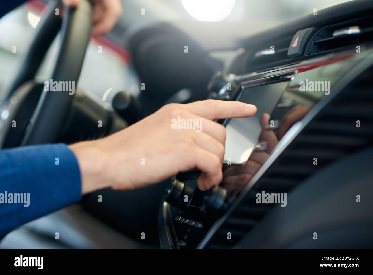 Messa a fuoco selettiva del display del sensore a contatto con l'uomo irriconoscibile in auto. Primo piano sull'utilizzo del pannello di controllo all'interno del veicolo, dell'abitacolo, che controlla le impostazioni della vettura intelligente. Concetto di veicoli, tecnologia. Foto Stock