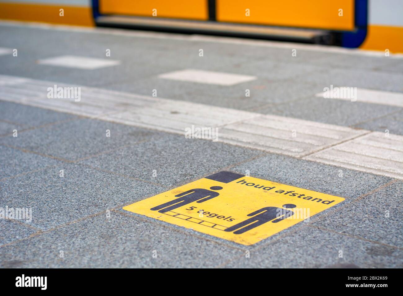 Misure di coronavirus sulla stazione ferroviaria a piattaforma nei Paesi Bassi. Cartello adesivo giallo che richiede di mantenere cinque piastrelle di distanza per covid-19 Foto Stock