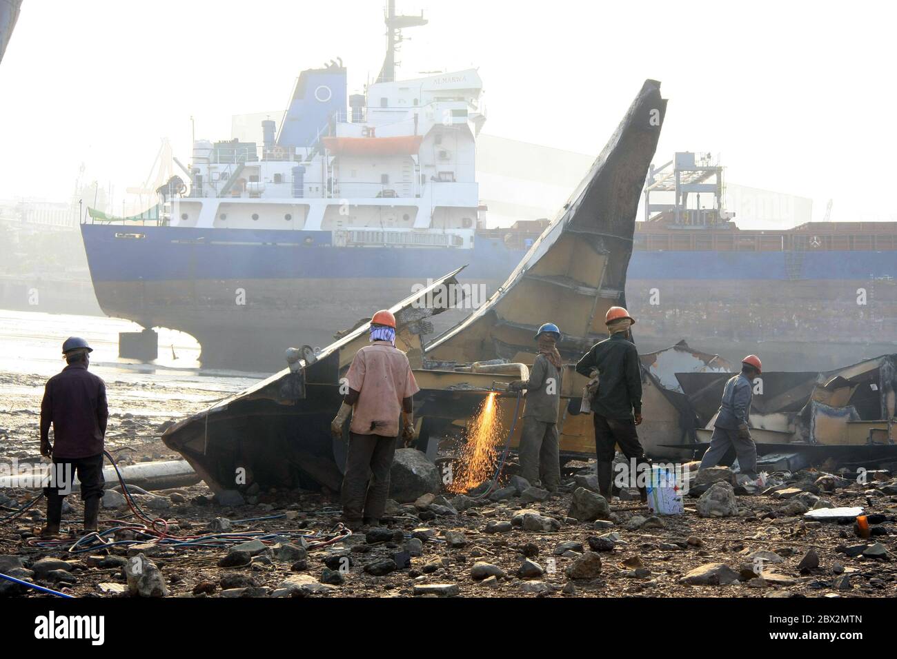 Shipbreaking Yard a Darukhana, Mumbai, India – smantellamento DI INS Vikrant con rottami di metallo e lavoratori in background Foto Stock