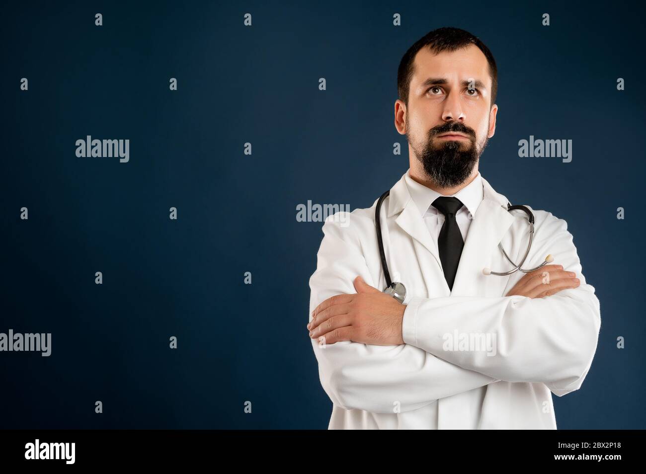 Ritratto di medico maschile con stetoscopio in uniforme medica aspetto sicuro eroe-shot posando su uno sfondo blu isolato. Foto Stock