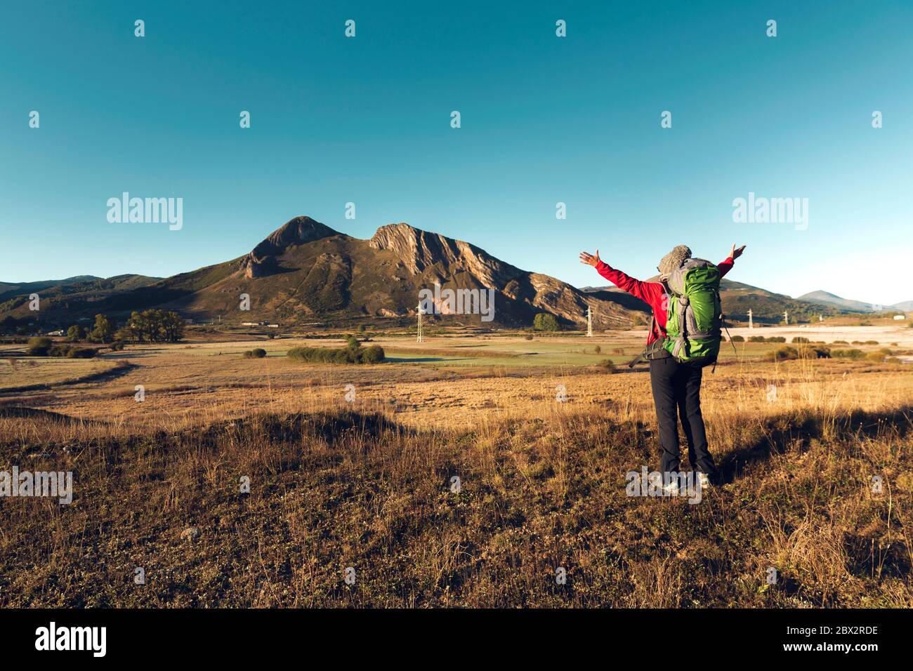 Vista posteriore di una donna con le braccia sollevate e uno zaino, godendo la vista Foto Stock