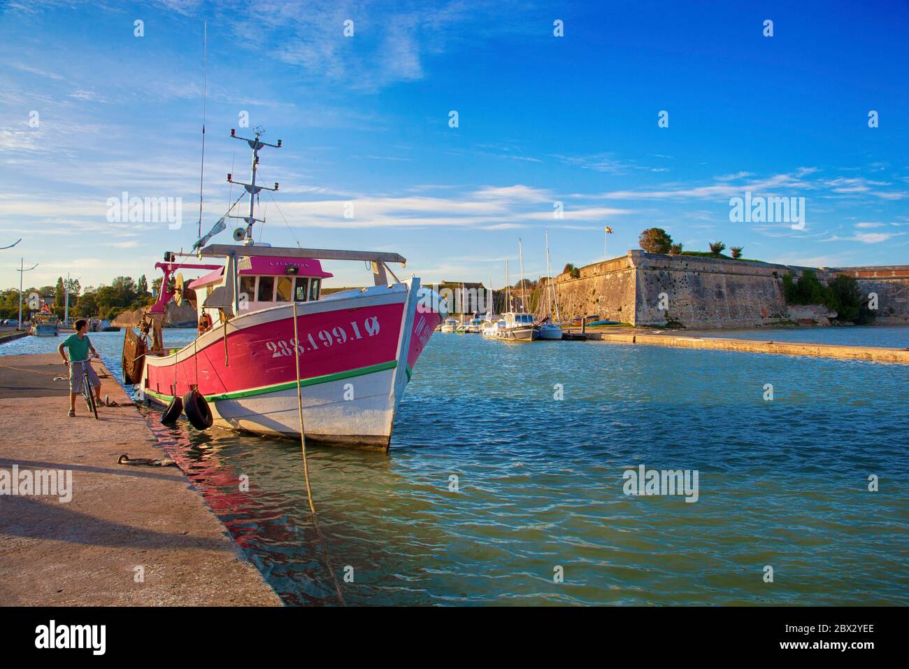 Francia, Charente-Maritime (17), jeune cycliste et Bateau de pêche à quai au Château-d'Oléron Foto Stock