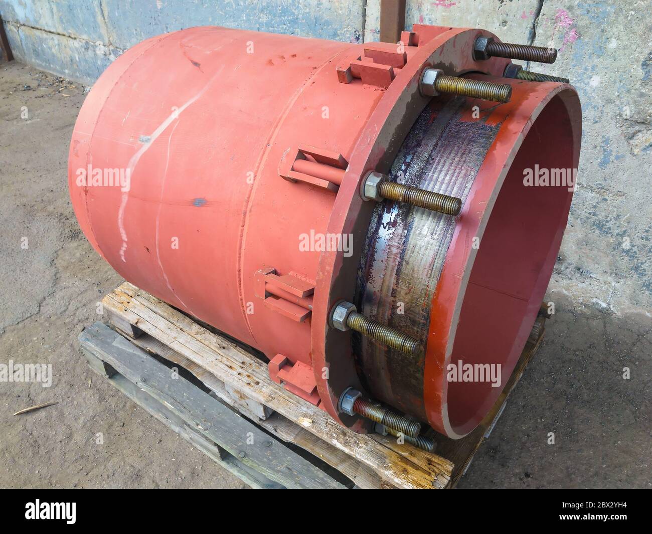 Giunto di espansione del premistoppa rosso per il riscaldamento della rete principale su pavimento in cemento. Concetto di calore e potenza. Foto Stock