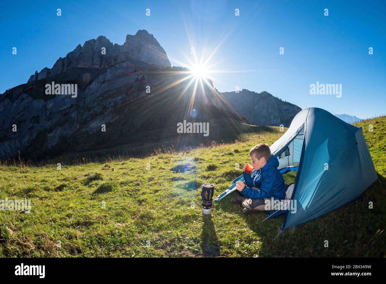 Francia, alta Savoia (74), Massiccio del Monte Bianco, Passy, Lachat d'en Haut, giovane escursionista che ha la sua colazione ai piedi dell'Aiguille de Varan (2544 m) dopo una notte in bivacco Foto Stock