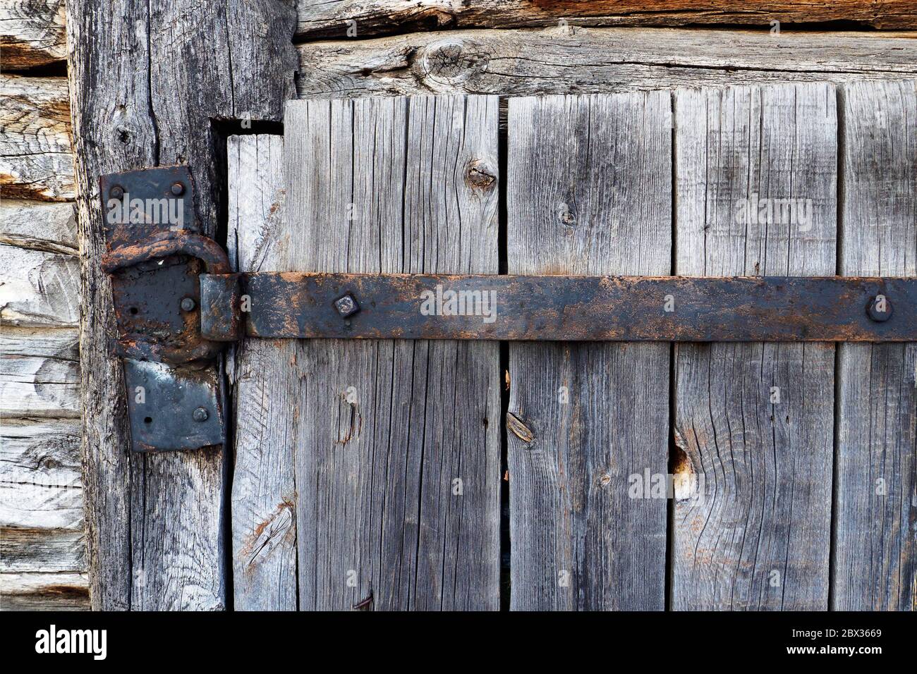 cerniera in ferro invecchiato arrugginita grigia su vecchio sportello in legno Foto Stock