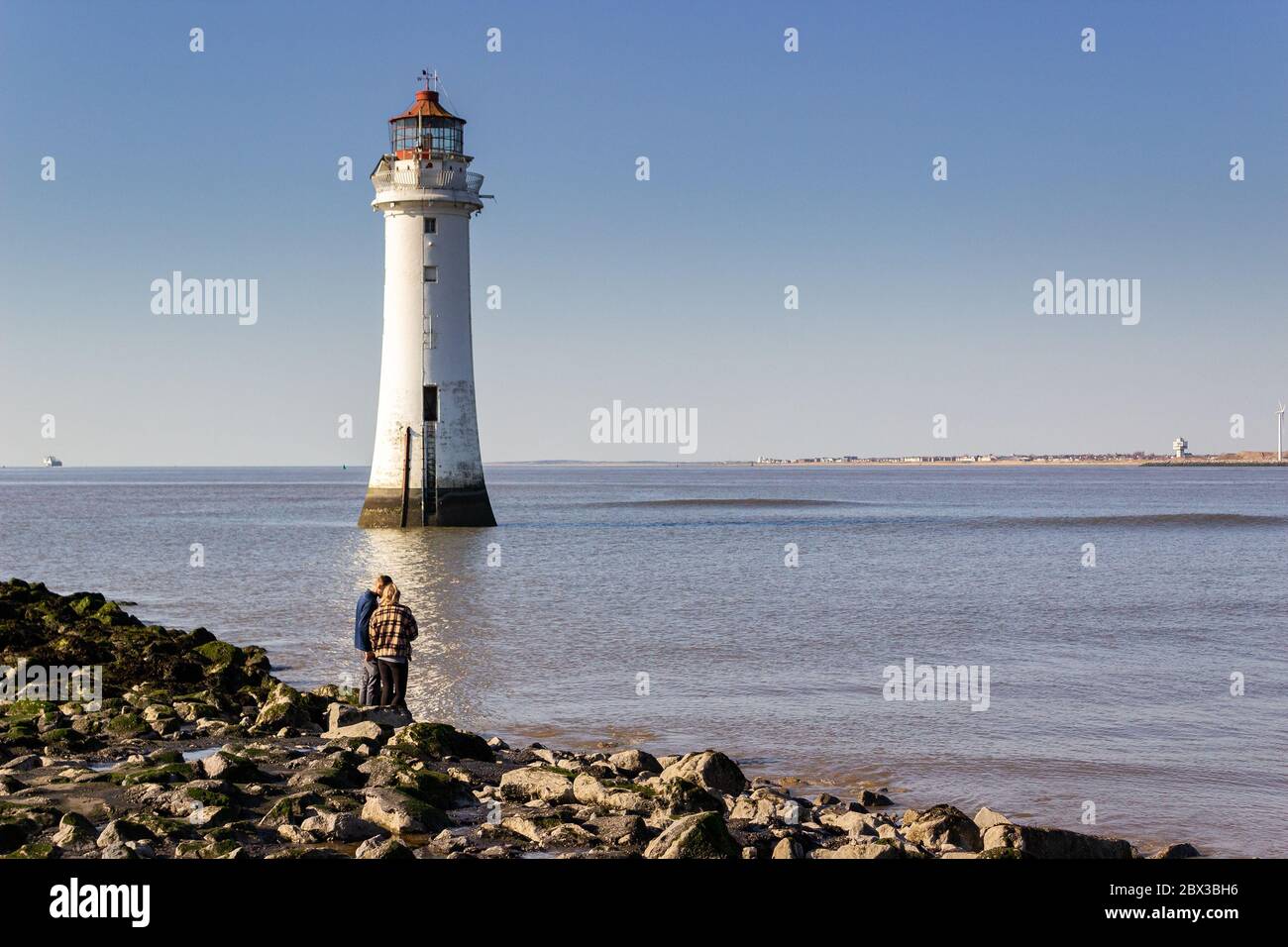 Coppia sul mare di rottura dal faro di New Brighton, acque calme sul fiume Mersey, New Brighton, Wallasey Foto Stock