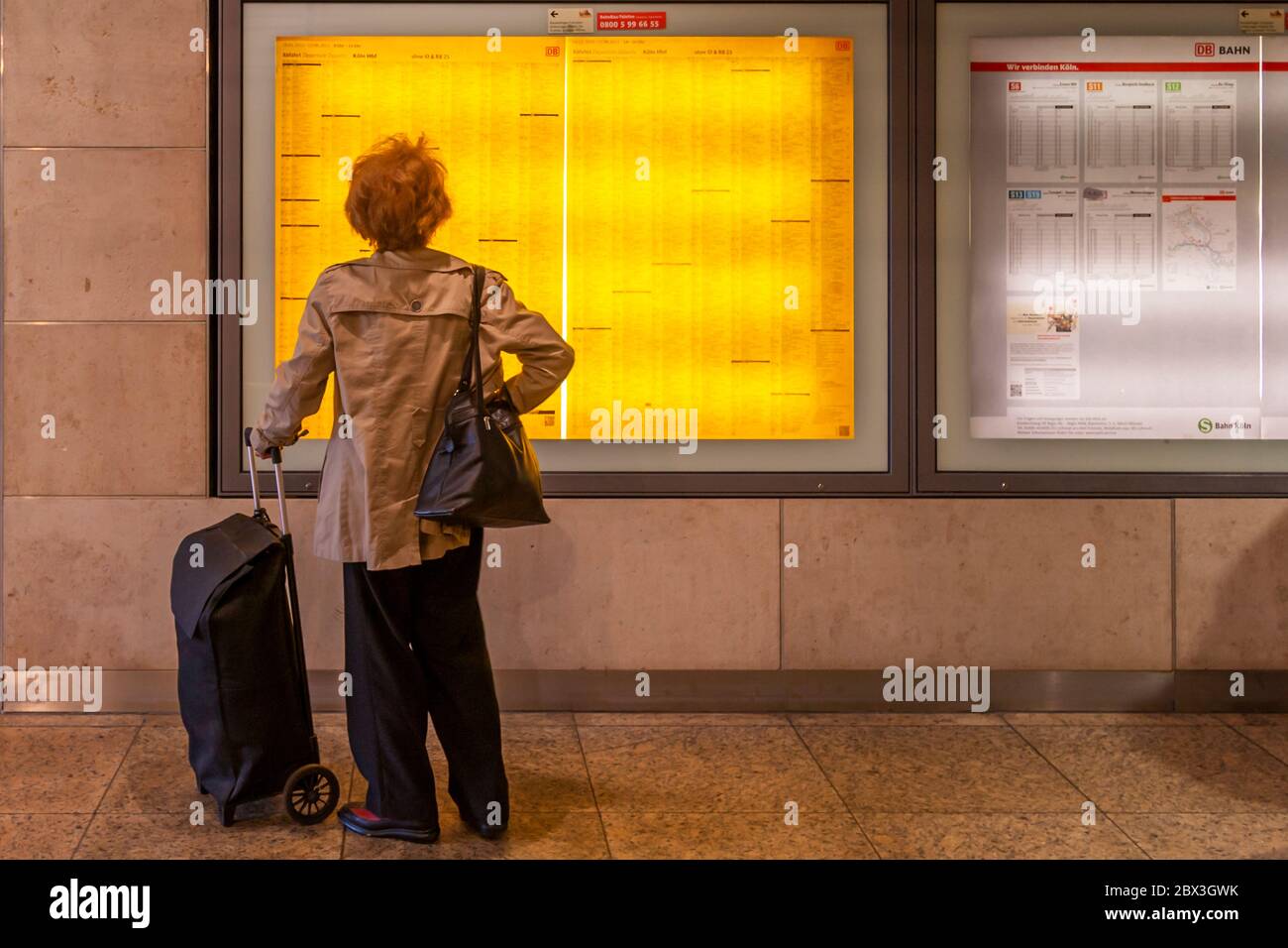 Un viaggiatore studia l'orario postato alla stazione centrale di Colonia, Germania Foto Stock