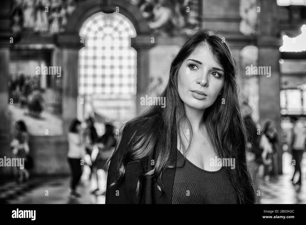 Una donna portoghese attende nella stazione ferroviaria di São Bento con piastrelle azulejo che adornano le mura della città di Porto, in Portogallo Foto Stock