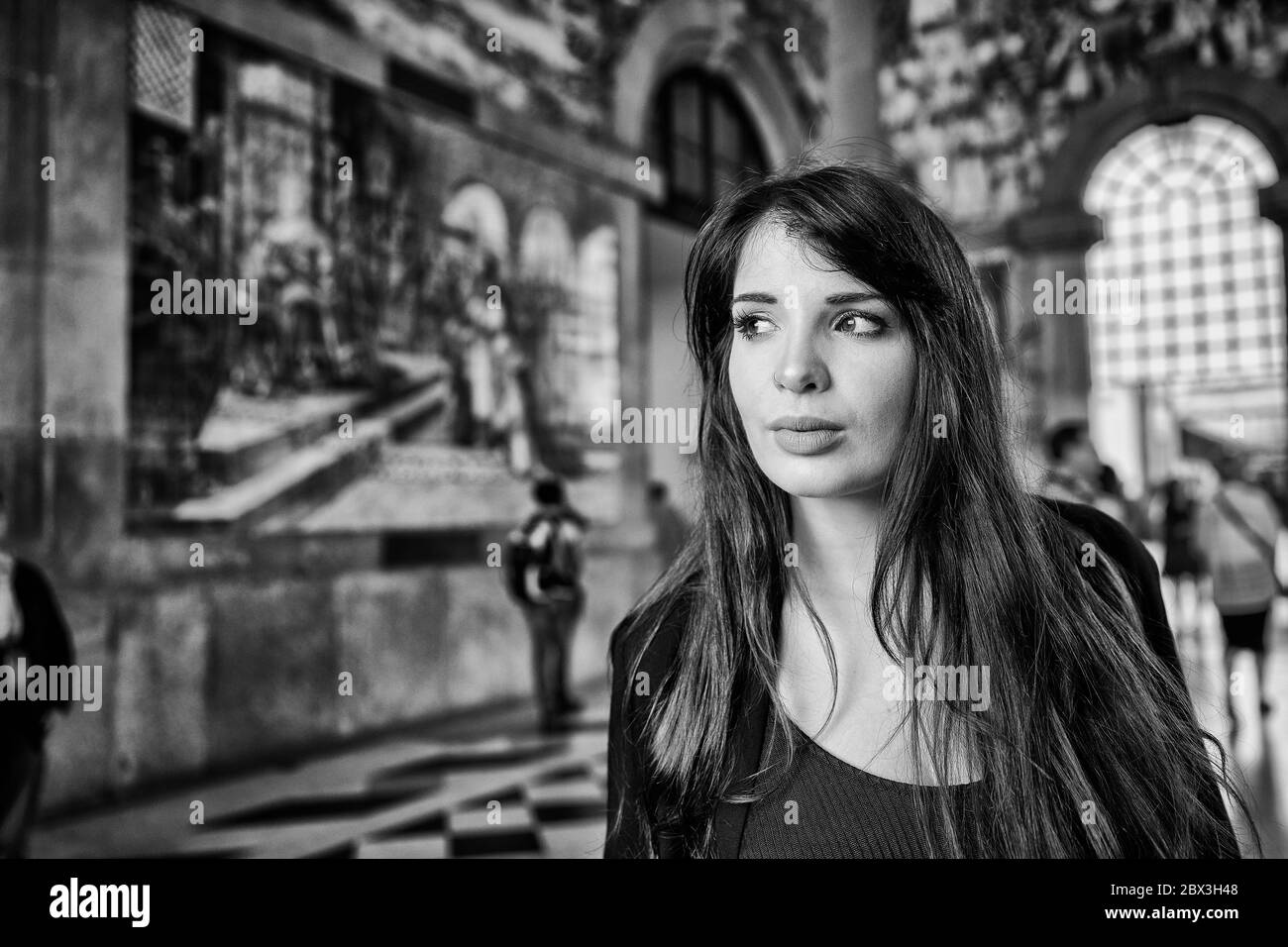 Una donna portoghese attende nella stazione ferroviaria di São Bento con piastrelle azulejo che adornano le mura della città di Porto, in Portogallo Foto Stock