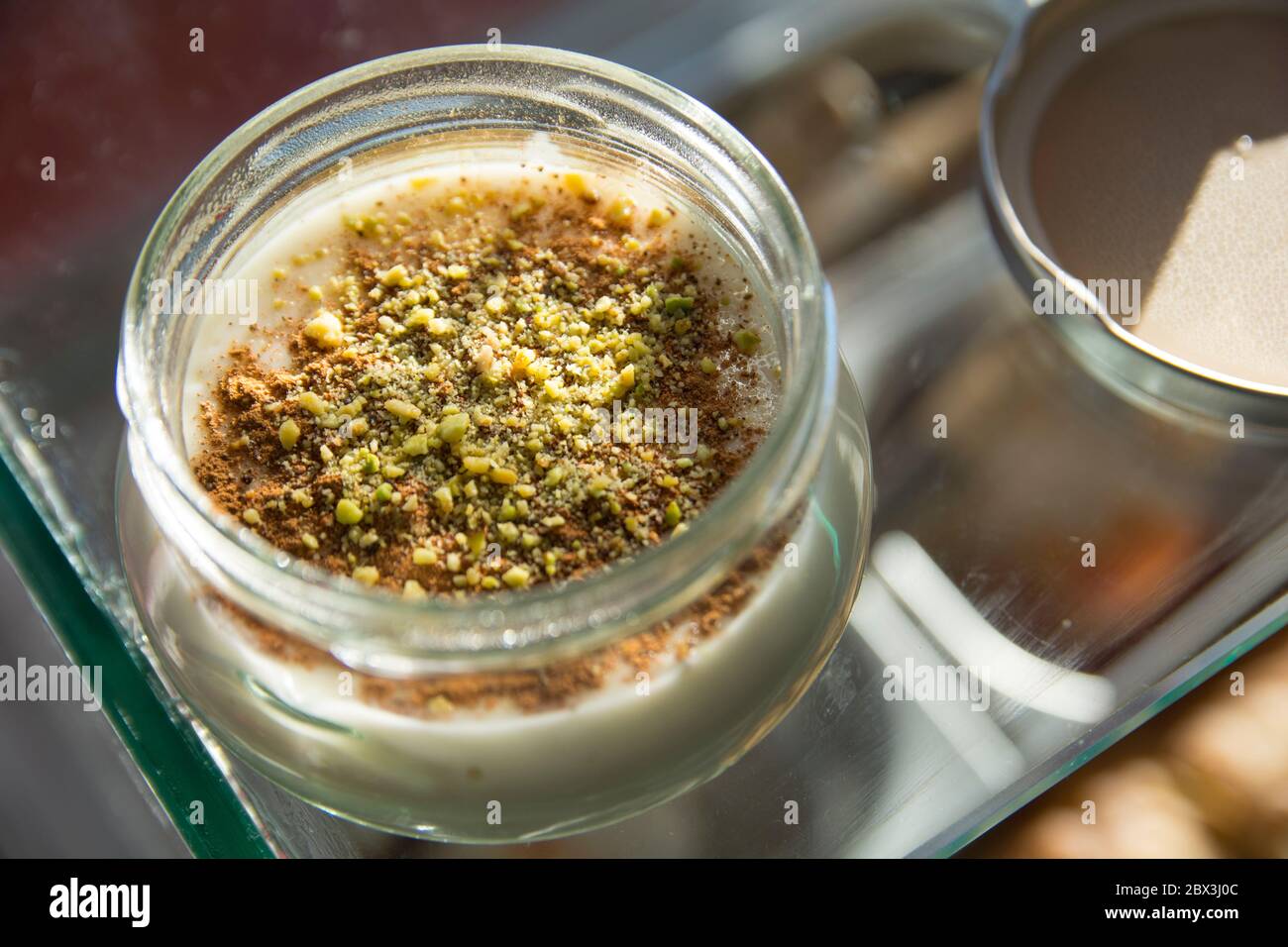 Vista dall'alto di una ciotola di Sutlac (Sütlaç) - dessert tradizionale turco aromatico, budino di riso cremoso con cannella e pistacchi, servito su un AN nero Foto Stock