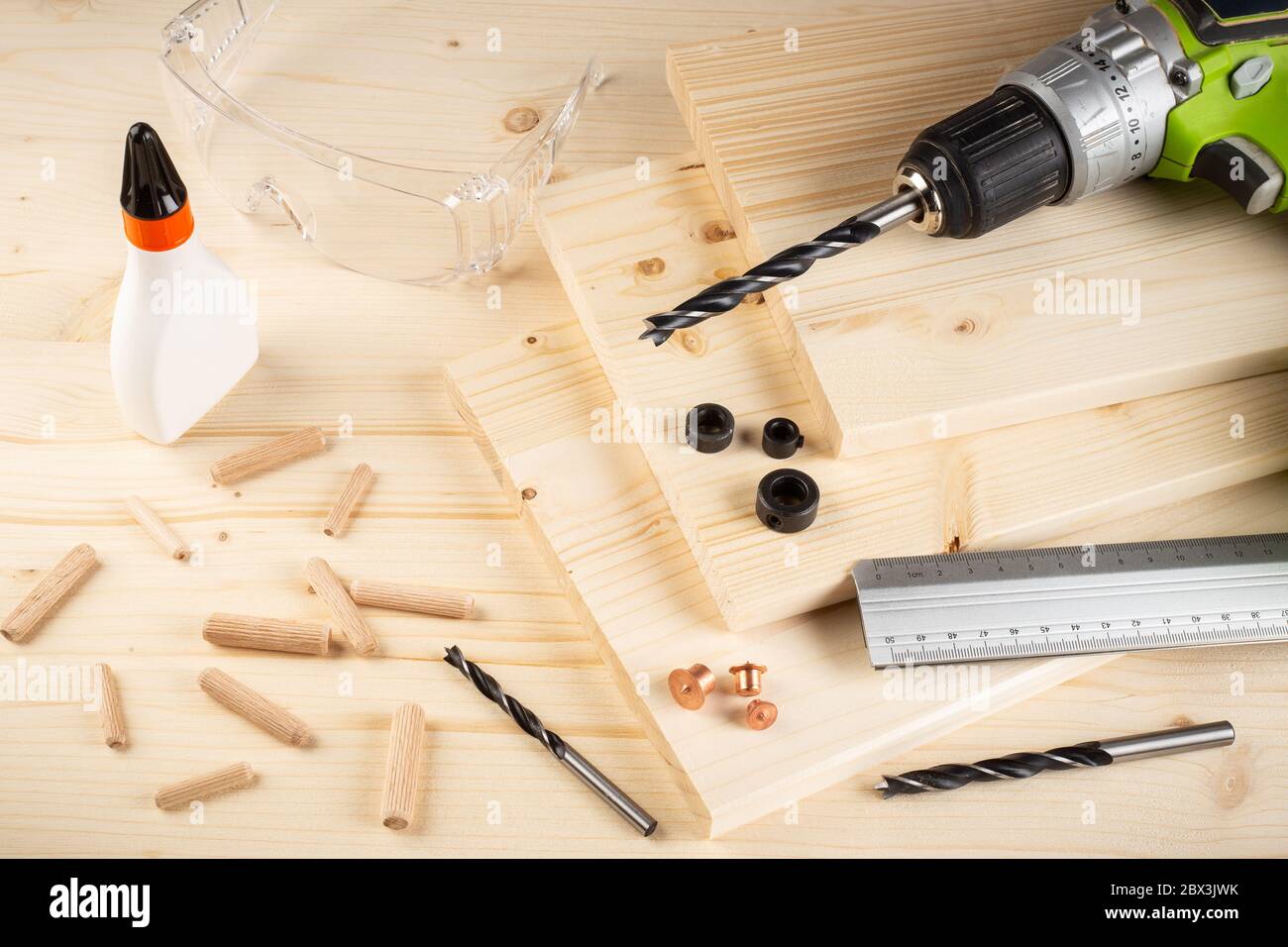 perni di giunzione in legno per punte di riferimento per trapano colla tavole di legno vetri di sicurezza cacciavite a batteria e utensili su fondo in abete rosso. Carpentiere industria funiture fare Foto Stock