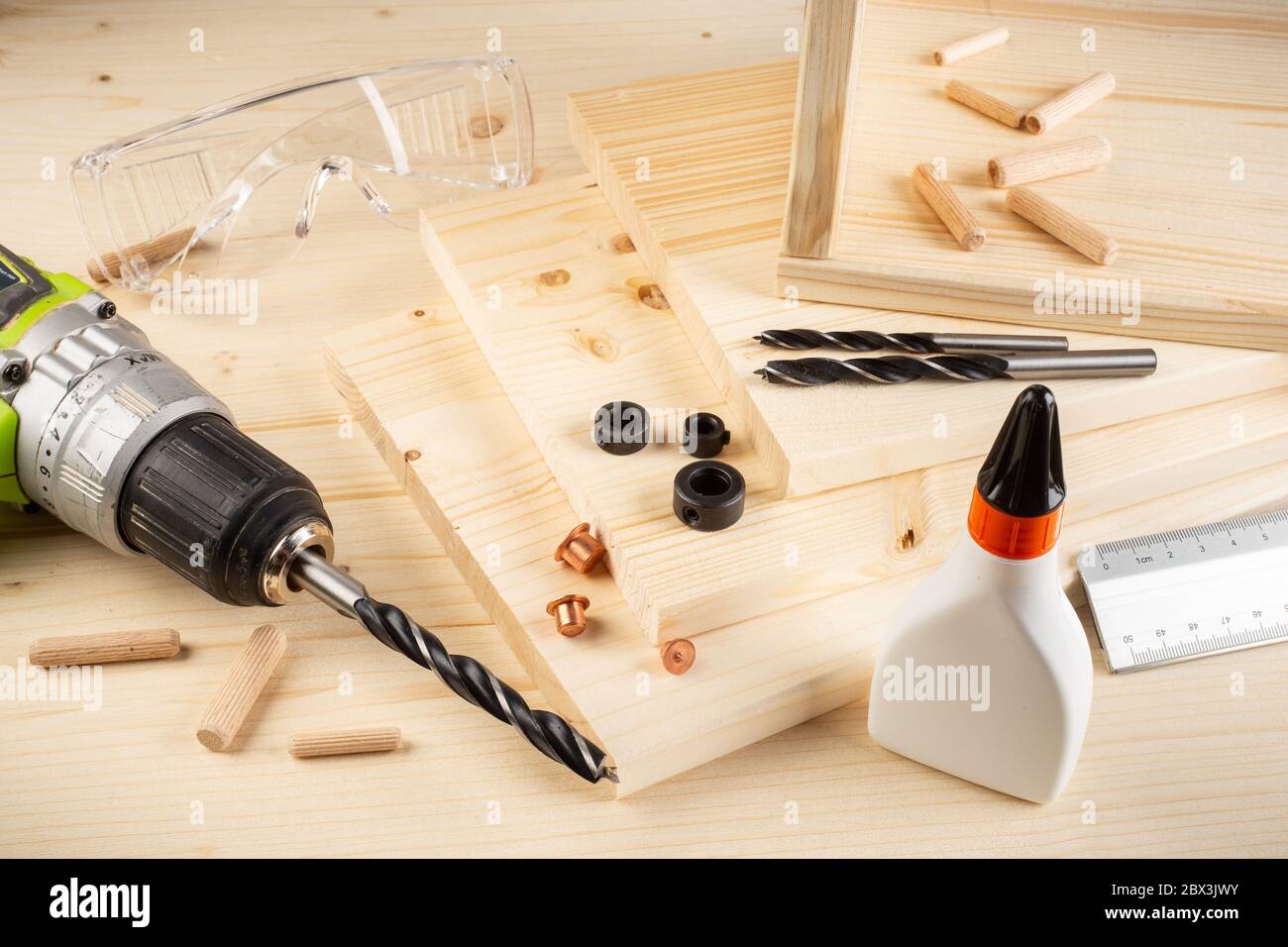 perni di giunzione in legno per punte di riferimento per trapano colla tavole di legno vetri di sicurezza cacciavite a batteria e utensili su fondo in abete rosso. Carpentiere industria funiture fare Foto Stock