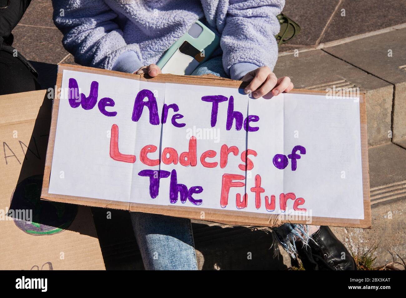 Giovane donna tagliata e irriconoscibile, porta un segno fatto a mano - noi siamo i leader del futuro Foto Stock