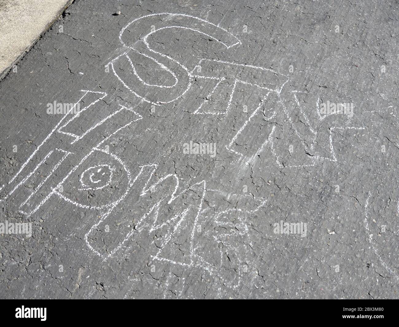 Primo piano di marciapiede gesso con lettura di testo Stay Home, un messaggio di speranza scritto da membri della comunità su un marciapiede di quartiere durante i blocchi relativi a uno scoppio del coronavirus COVID-19, San Ramon, California, 14 aprile 2020. () Foto Stock