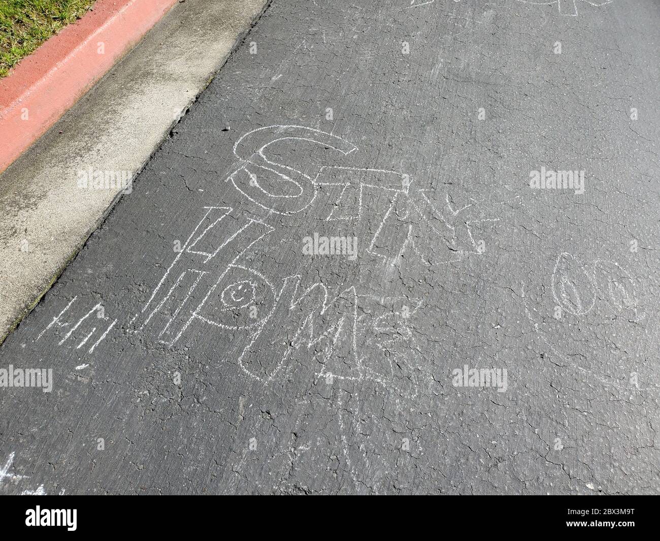 Primo piano di marciapiede gesso con lettura di testo Stay Home, un messaggio di speranza scritto da membri della comunità su un marciapiede di quartiere durante i blocchi relativi a uno scoppio del coronavirus COVID-19, San Ramon, California, 14 aprile 2020. () Foto Stock