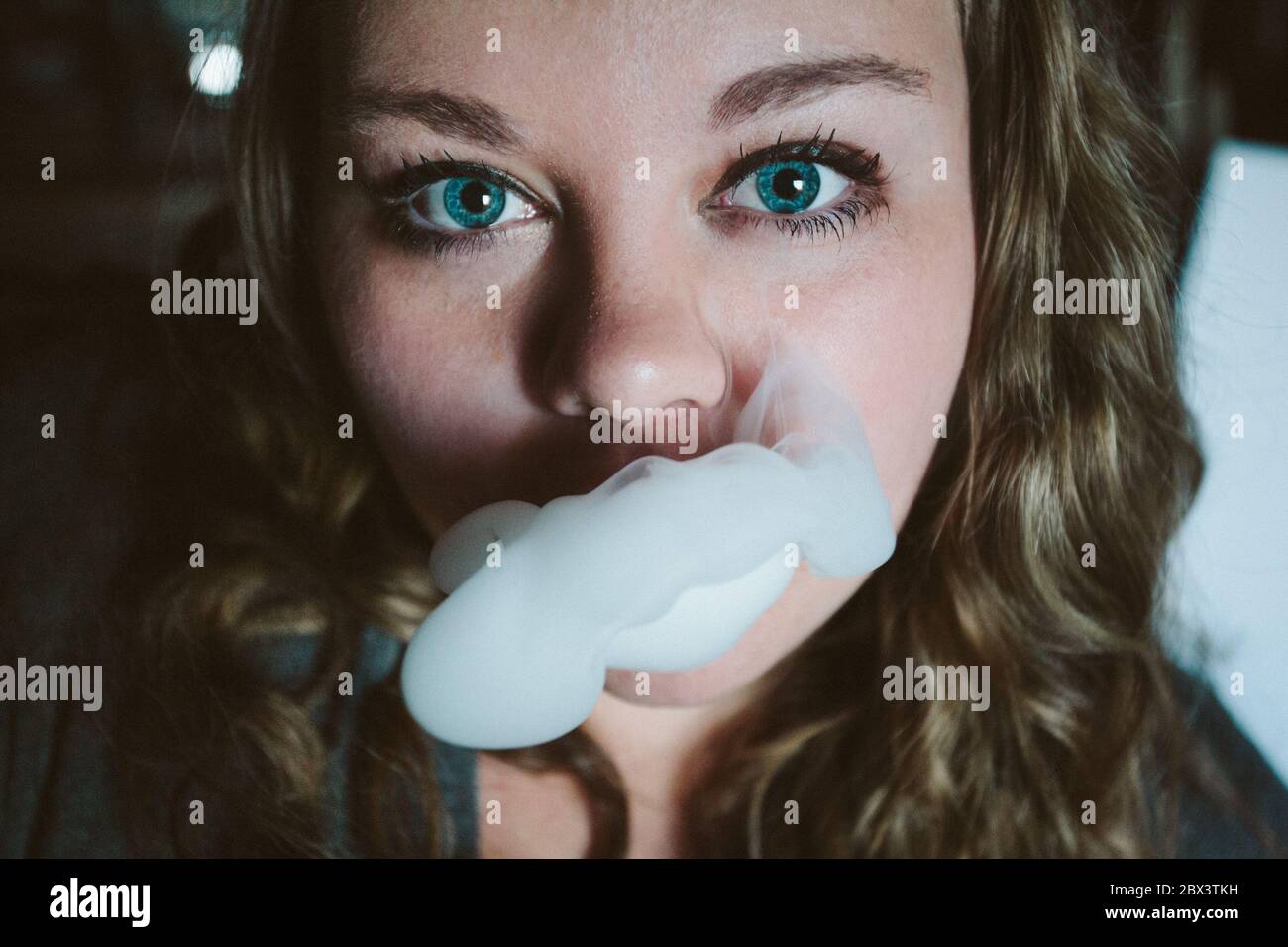 Una giovane donna fuma una sigaretta di cannabis Foto Stock