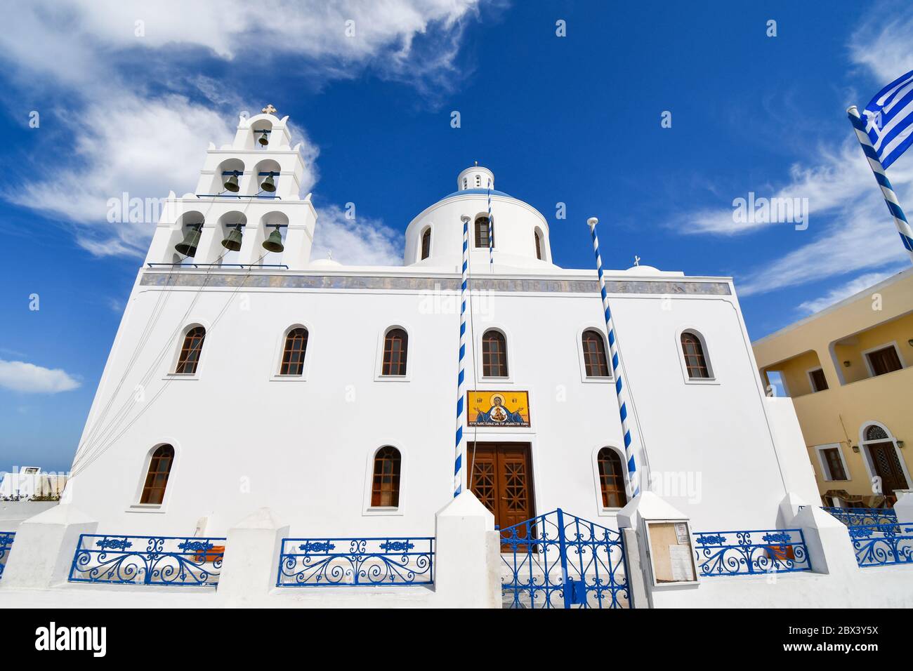 La Chiesa di Panagia Platsani con una bandiera greca che vola nel villaggio collinare di Oia, sull'isola di Santorini, Grecia. Foto Stock