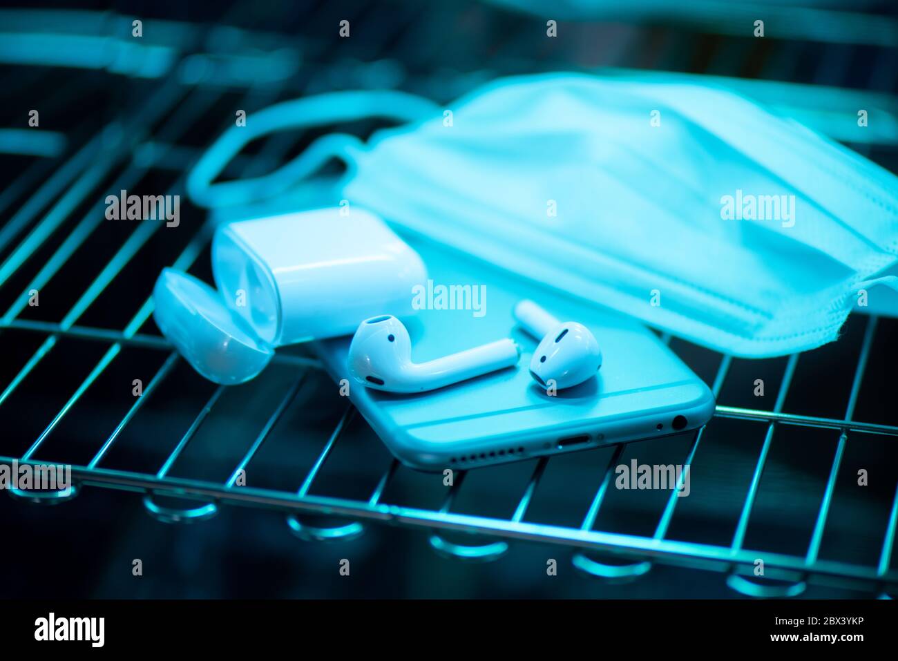 Sterilizzazione con luce UV di smartphone e auricolari. Concetto di prevenzione COVID-19. Foto Stock