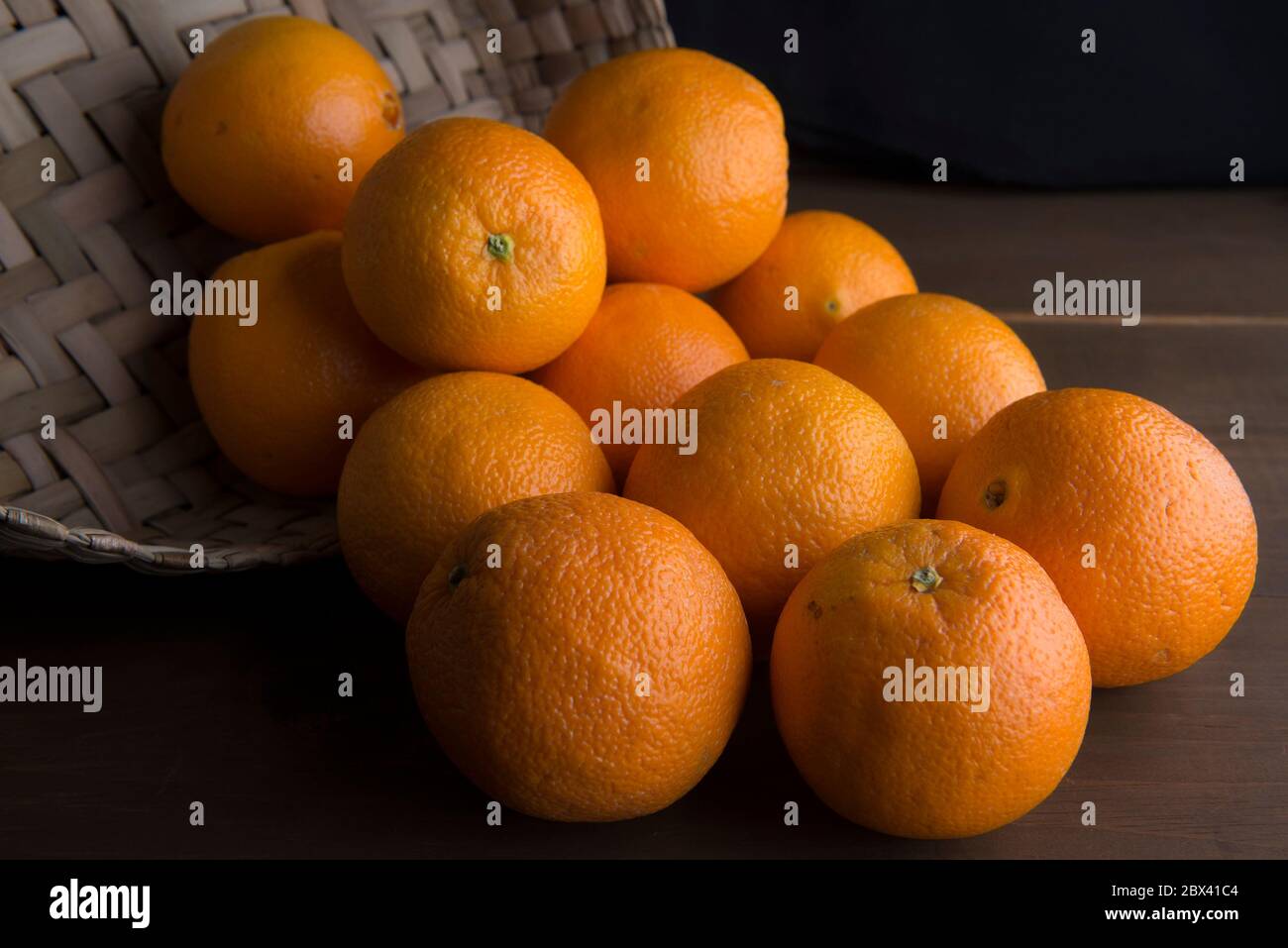 la vita still, la chiave bassa o la fotografia di alimento scuro, arance in un cestino su un tavolo Foto Stock