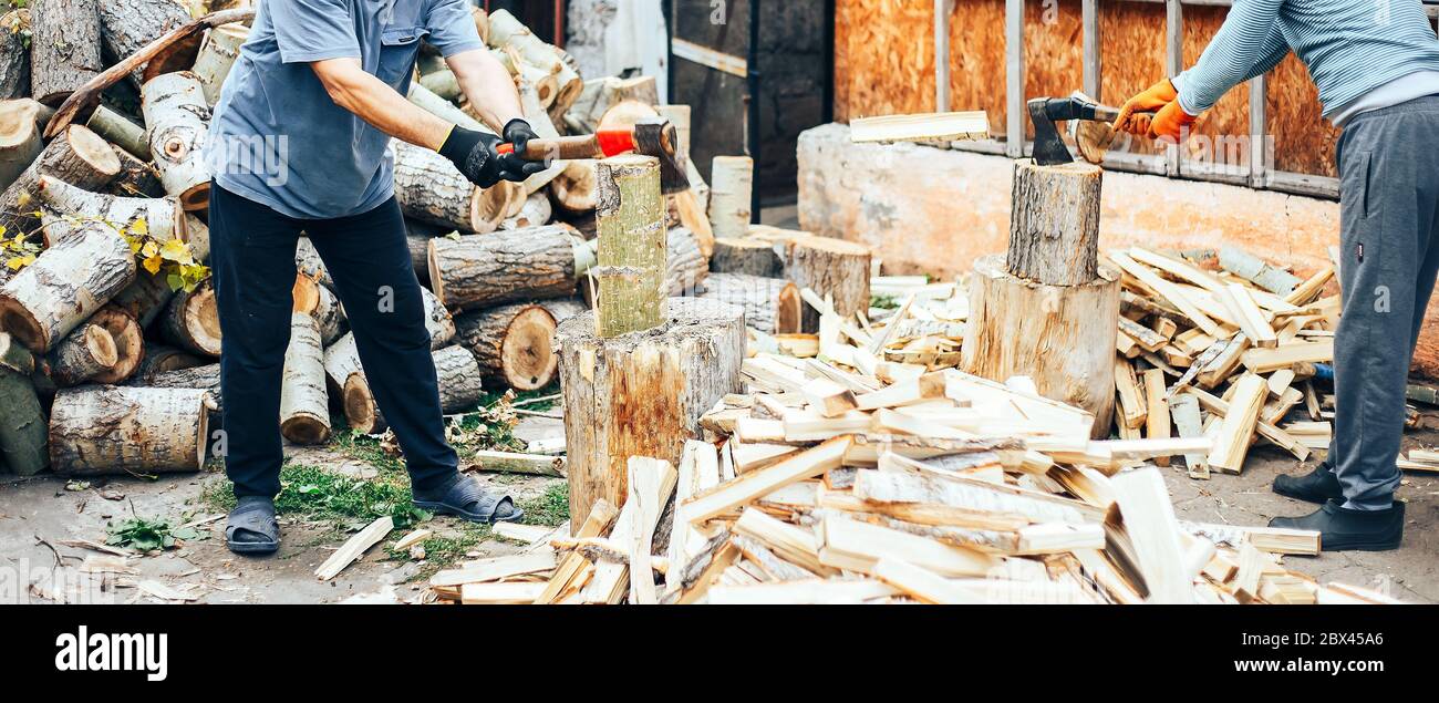 Uomo in jeans e camicia a scacchi in piedi vicino al moncone con ascia in mani lungo banner Foto Stock