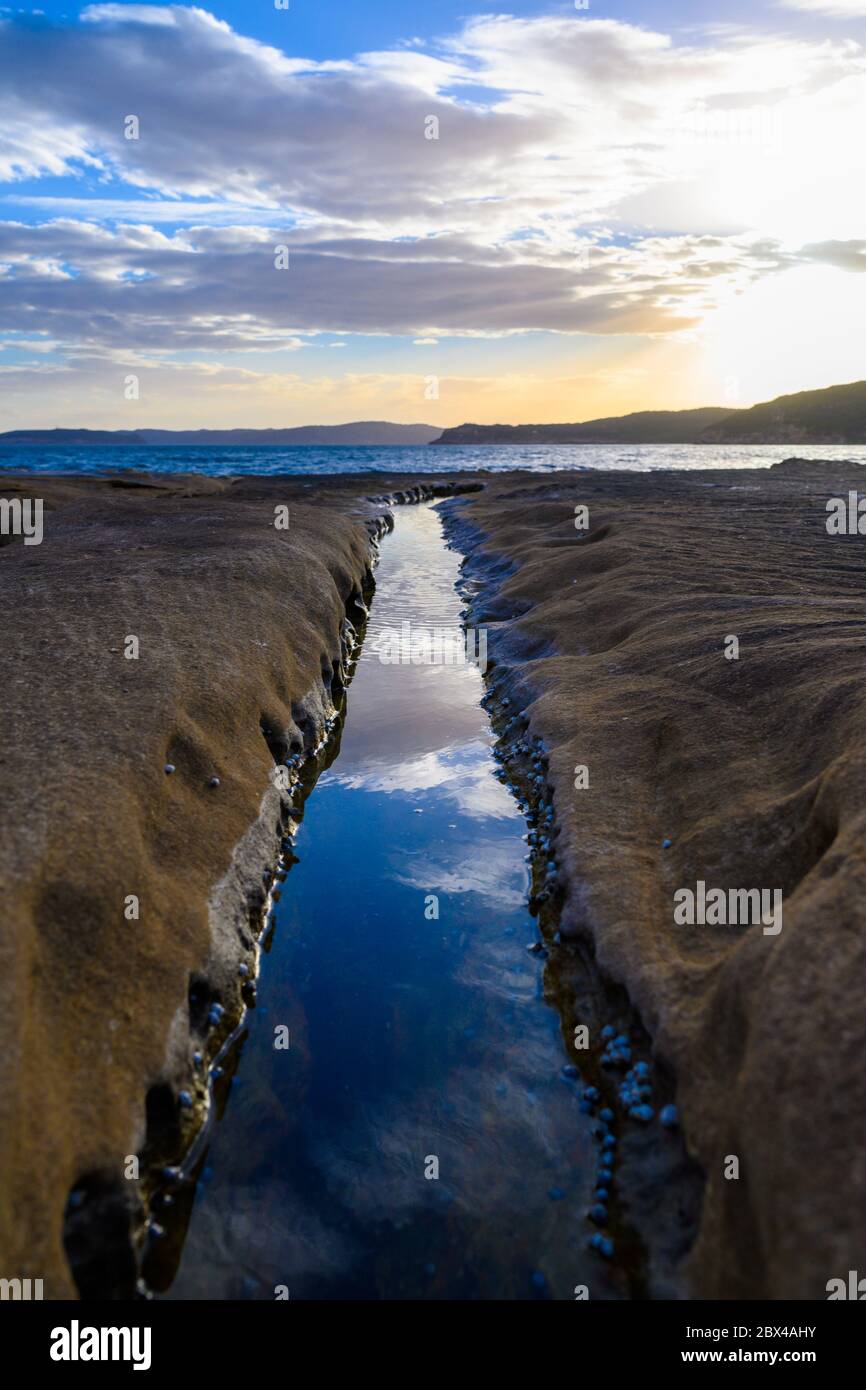 Piattaforma rocciosa con acqua che riflette il cielo Foto Stock
