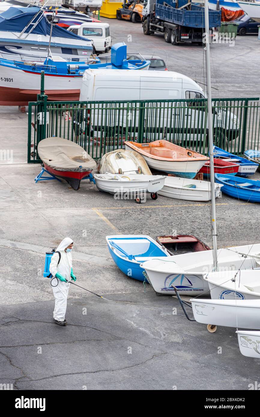 L'uomo disenfects il tarmac intorno al porto e banchine , vestito con un vestito protettivo e indossando una maschera, durante la seconda fase di de-escalation da Covid 19 Foto Stock