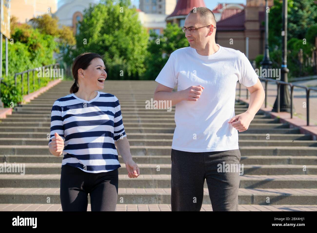 Coppia che corre sulle scale in città, uomo maturo e donna insieme Foto Stock