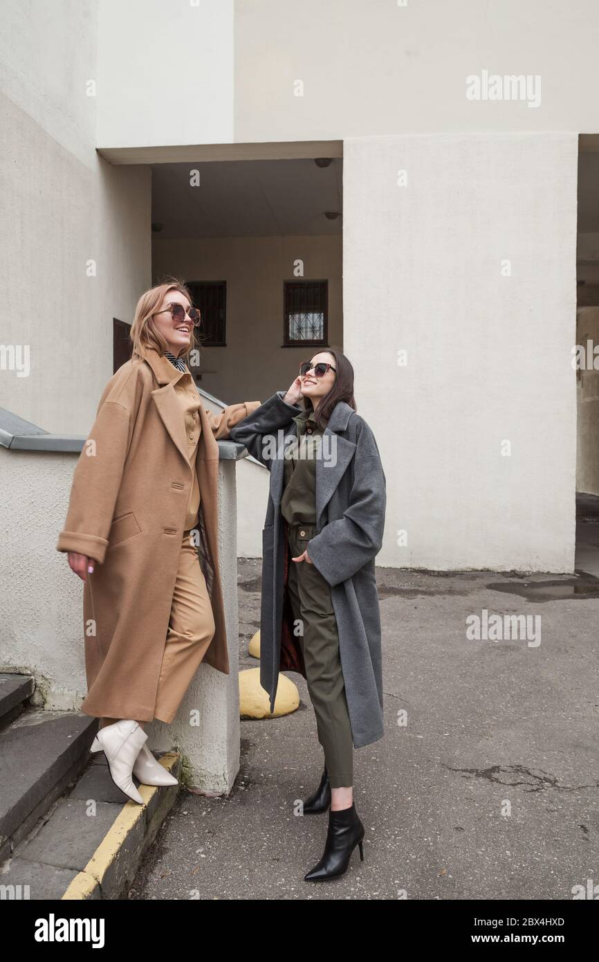 Look casual. Stile Street. Ritratto di moda all'aperto di due giovani belle donne che indossano abiti alla moda, ridendo e guardando via, in posa Foto Stock