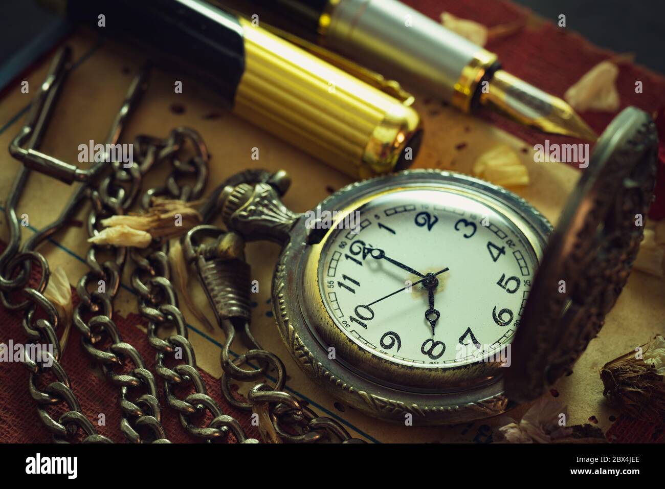 Orologio da tasca vintage e penna di ottone sul vecchio libro. Alle 8 del mattino. Concetto di istruzione e stile vintage. Foto Stock