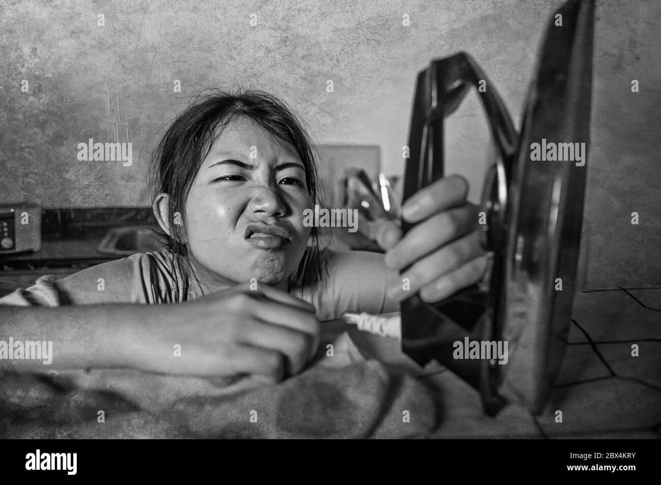 Ritratto di giovane abbastanza frustrato e stressato asiatico cinese donna che tiene il ferro triste lavoro a casa cucina stirare vestiti stanchi e sopraffatti dentro Foto Stock