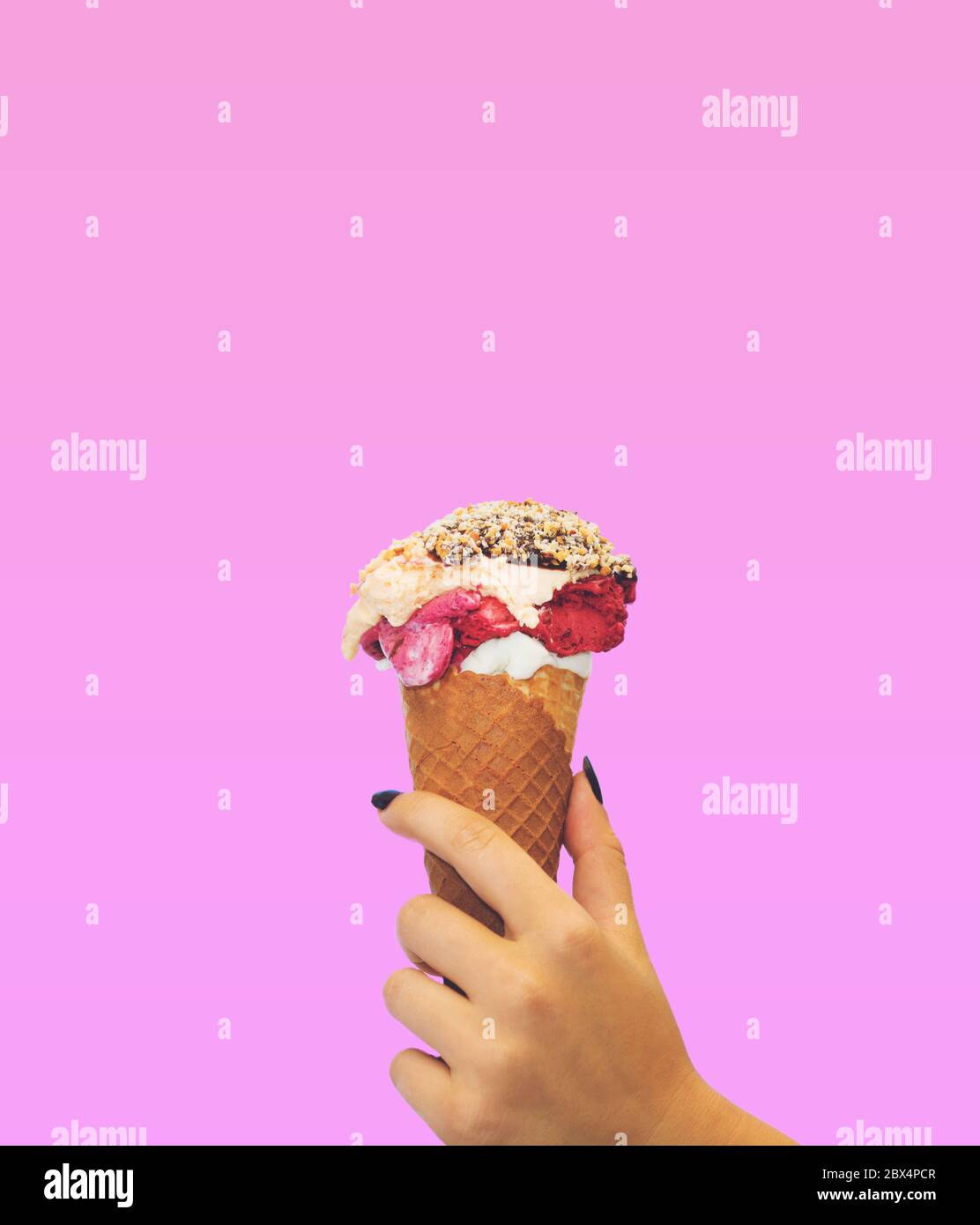 Cono gelato su sfondo rosa. La donna che tiene il gelato a mano Foto Stock