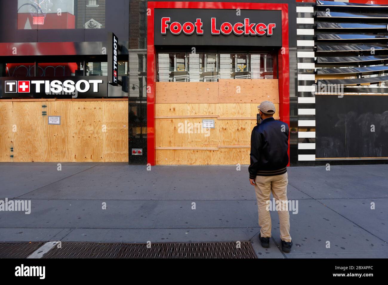 New York, 3 giugno 2020. Una persona scatta una foto di un Foot Locker e Tissot con finestre e porte a bordo in Herald Square dopo una recente ondata di furti/saccheggi organizzati in città su larga scala. I negozi si uniscono ad altre aziende in tutta la città, spaventate dai saccheggiatori, salendo su finestre e porte come misura precauzionale e inviando un messaggio di disperazione e disperazione a molti non abituati a vedere così tanti negozi chiusi in una città normalmente vivace e trafficata. Molte imprese sono state chiuse durante la pandemia di COVID-19. Foto Stock