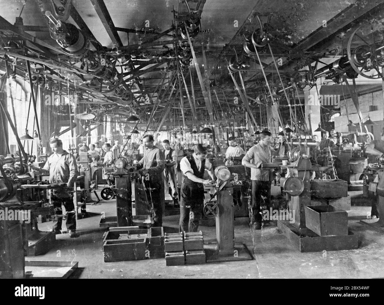 Una vista in fabbrica con cinghie di trasmissione non fissate, che ha rappresentato un elevato rischio per la salute dei lavoratori industriali. In tali officine non sono stati rari gravi incidenti industriali. La priorità della sicurezza sul lavoro è stata imposta dai sindacati attraverso decenni di lotta. Foto Stock