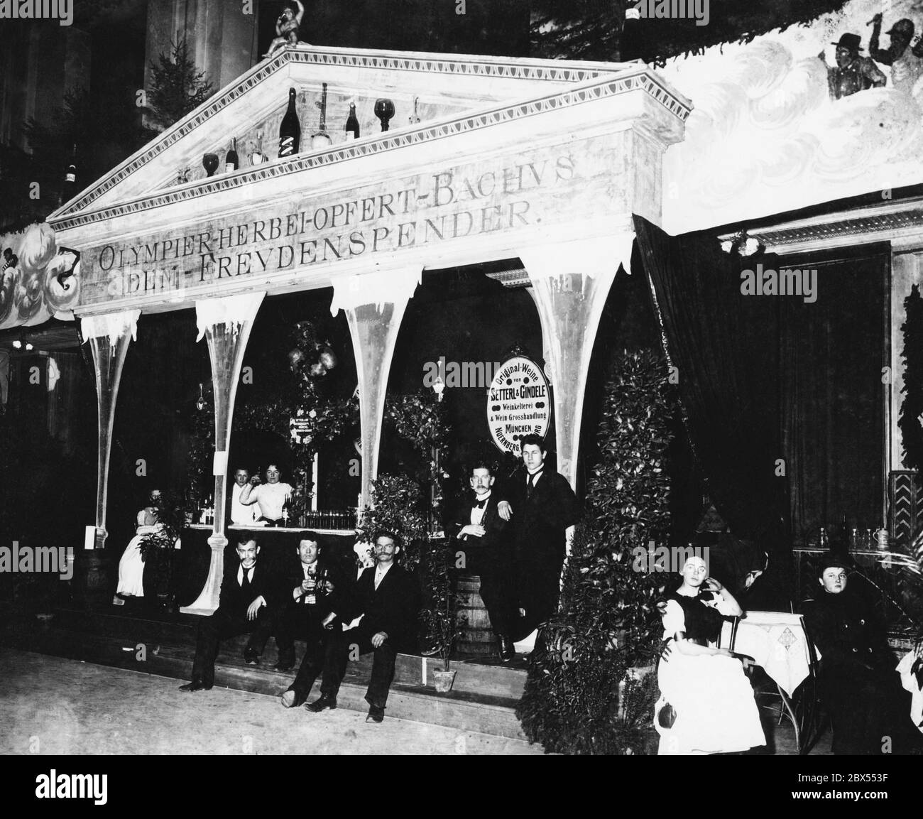 In occasione di una festa di carnevale a Monaco nel 1891, i Weinkelterei und Weingrosshandlung Setterl & Gindele di Monaco, Norimberga e Augusta avevano trasformato il proprio bar in un antico tempio romano. Questo porta l'iscrizione 'Olympier herbei oppert Bachus dem Freudenspender' e nella capitale sono bottiglie di vino e bicchieri invece di statue. La fotografia mostra i camerieri e le cameriere del bar. Foto Stock