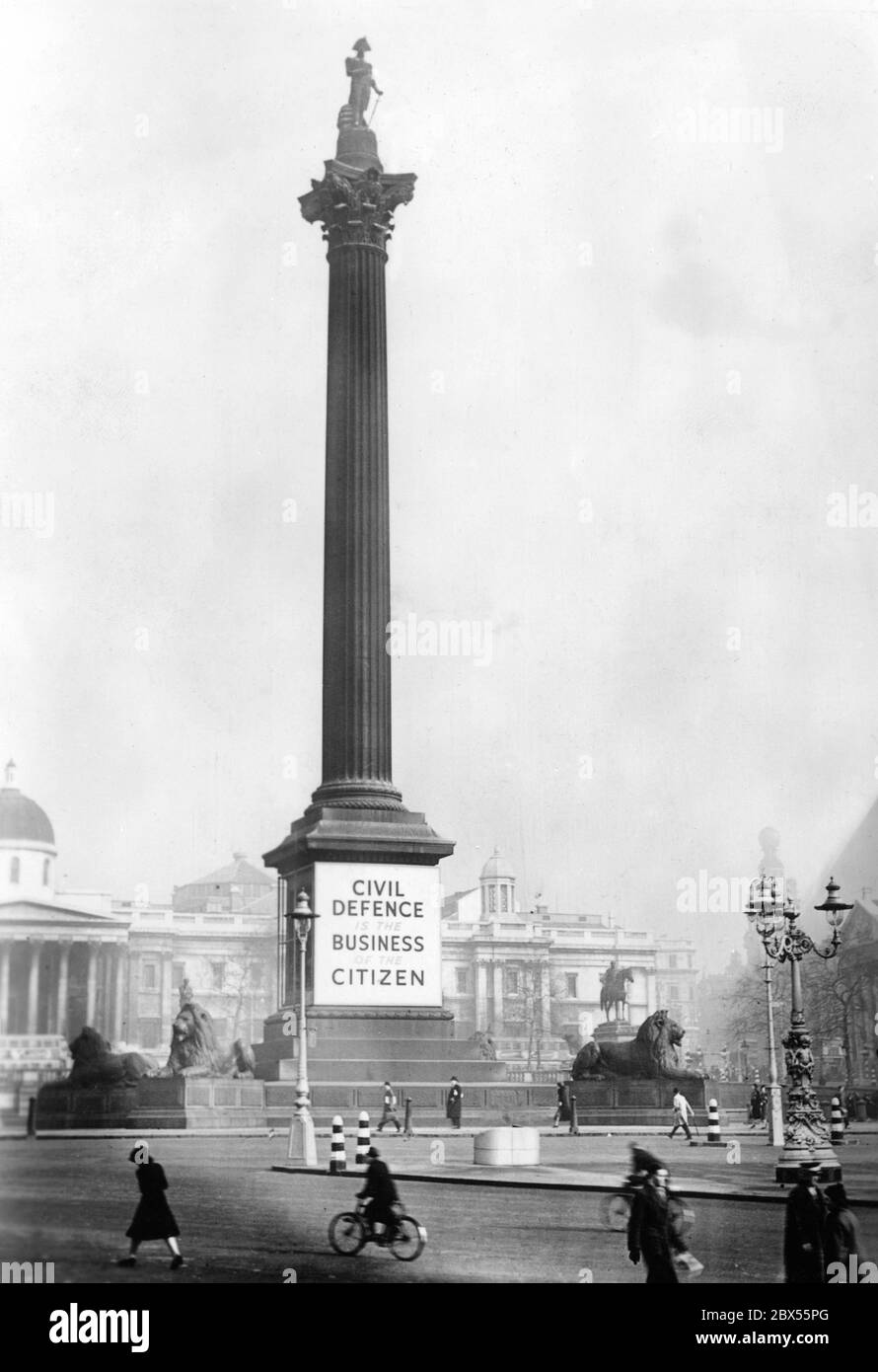 Un poster pubblicitario 'Difesa civile' è collocato alla base della colonna Nelson in Trafalgar Square. Foto Stock