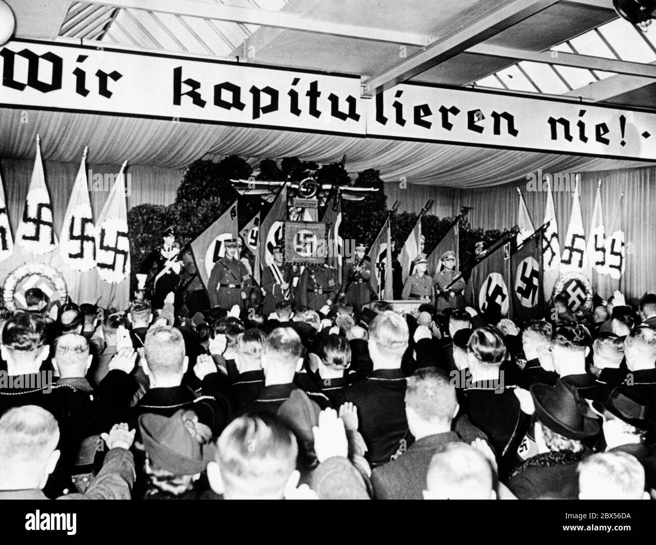 Il banner 'Wir kaptiulieren nie' (non capitoliamo mai) durante una riunione di partito a Berlino. Foto Stock