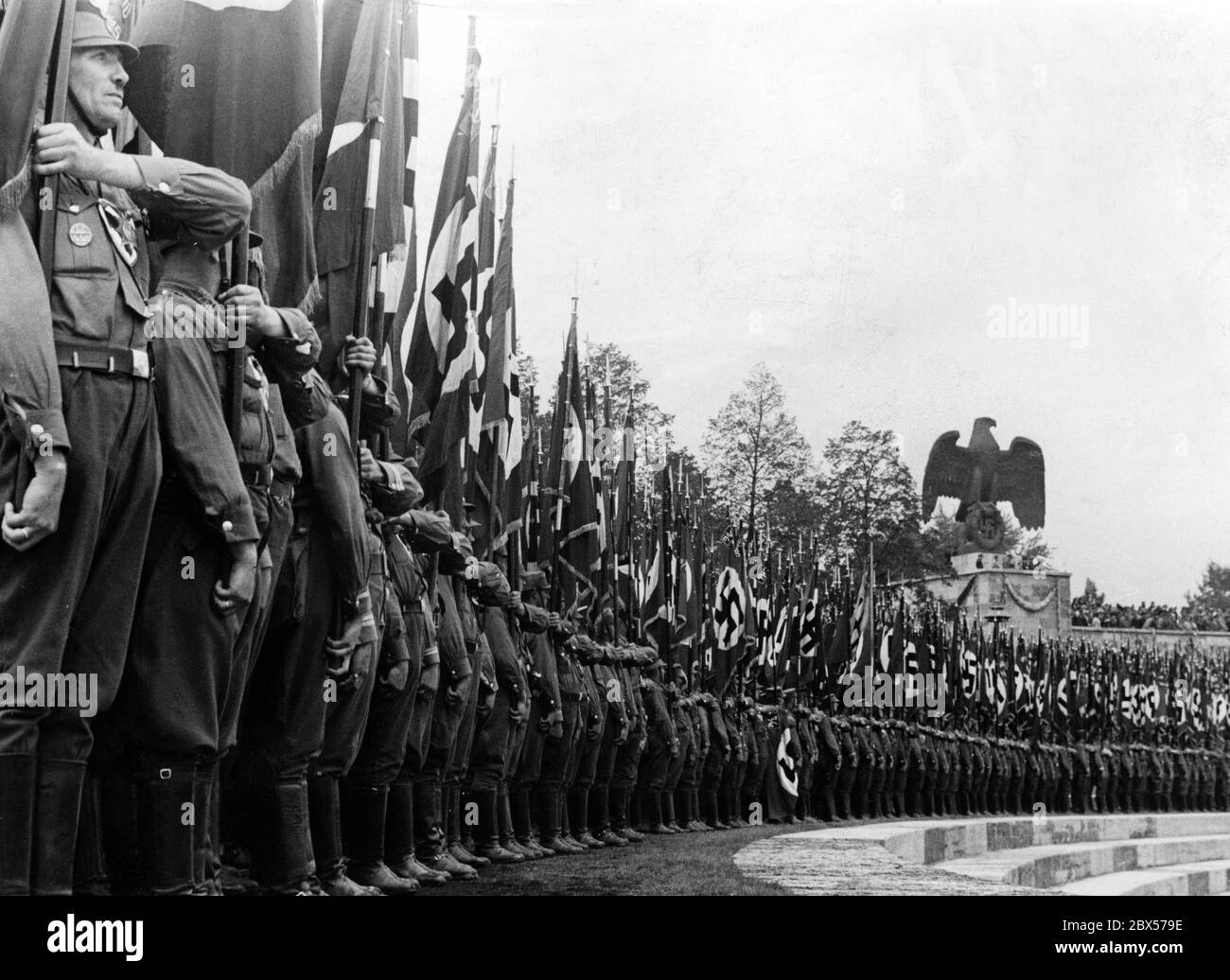 Durante la marcia del giorno SA, SS e NSKK al Reichsparteitag der Arbeit (Congresso del Partito del lavoro del Reich), i portacolori di bandiera SA si schieravano accanto al rostro sopra la Luitpold Arena. Foto Stock