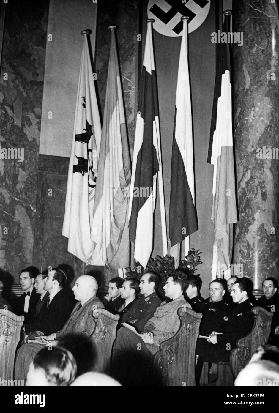 Il fronte laburista tedesco ha chiesto agli alleati il sostegno sotto forma di manodopera per poter garantire il mantenimento delle industrie importanti per la guerra. Le nazioni occupate sono state obbligate ad aiutare in questo campo. La foto mostra gli ospiti e i funzionari del fronte del lavoro tedesco (DAF) invitati a questo scopo. I loro paesi d'origine possono essere identificati dalle bandiere sullo sfondo: Fiandre, Spagna, Finlandia, Bulgaria e Francia (Vichy). Milioni di lavoratori sono stati reclutati sia da territori amici che occupati. Foto Stock