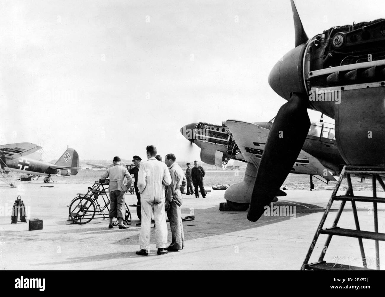 Nei locali della fabbrica di Junkers, il pilota (in bianco complessivo) di un Junkers Ju 87 discute i dettagli di un volo di prova. Sul lato sinistro della foto, l'ala sinistra e l'unità di coda di un Junkers Ju 88. Foto Stock