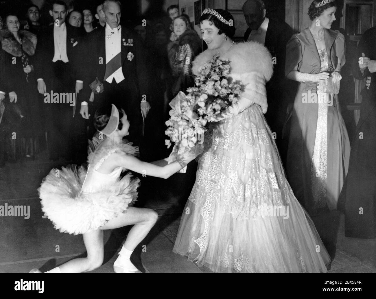 La Regina riceve un bouquet di fiori da Beryl Groom, al suo arrivo a teatro, per una rappresentazione della Scuola di Balletto di Sadler's Wells. Sulla sinistra si trova il conte di Lytton, il presidente dell'organo di governo del Vecchio Vic e Sandler's Wells. Foto Stock