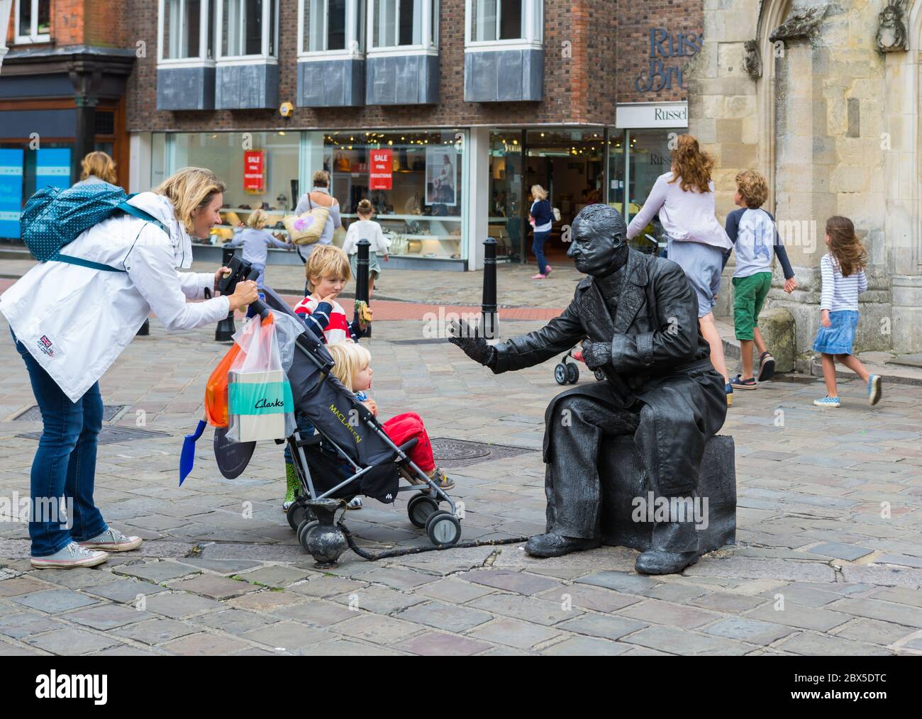 Statua vivente street performer con un vaso di raccolta in un centro commerciale a Chichester, West Sussex, in Inghilterra, Regno Unito. Foto Stock
