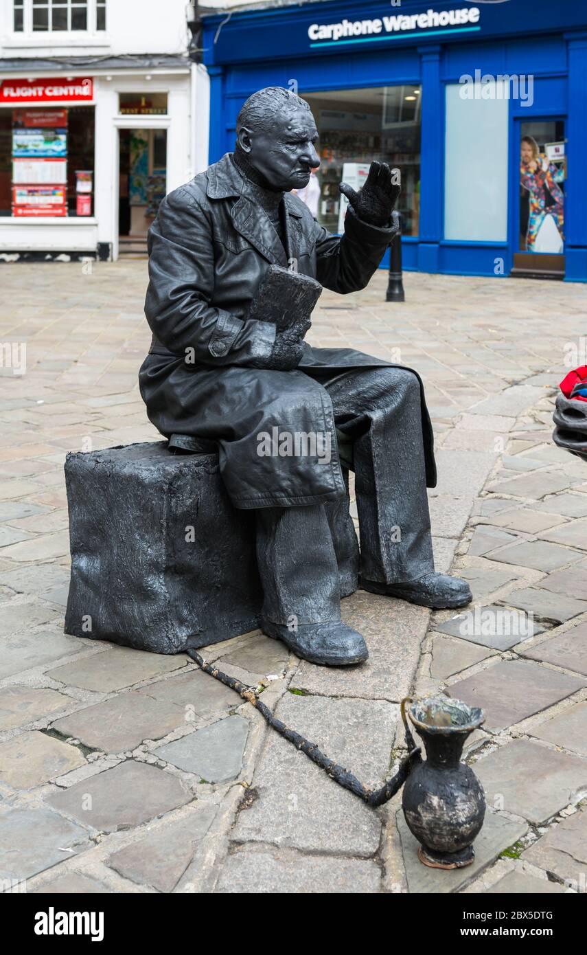 Statua vivente street performer con un vaso di raccolta in un centro commerciale a Chichester, West Sussex, in Inghilterra, Regno Unito. Foto Stock