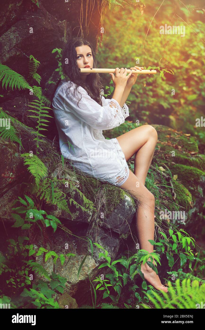 Bella dryad che gioca flauto in una foresta dopo la pioggia. Romanticismo e fantasia Foto Stock