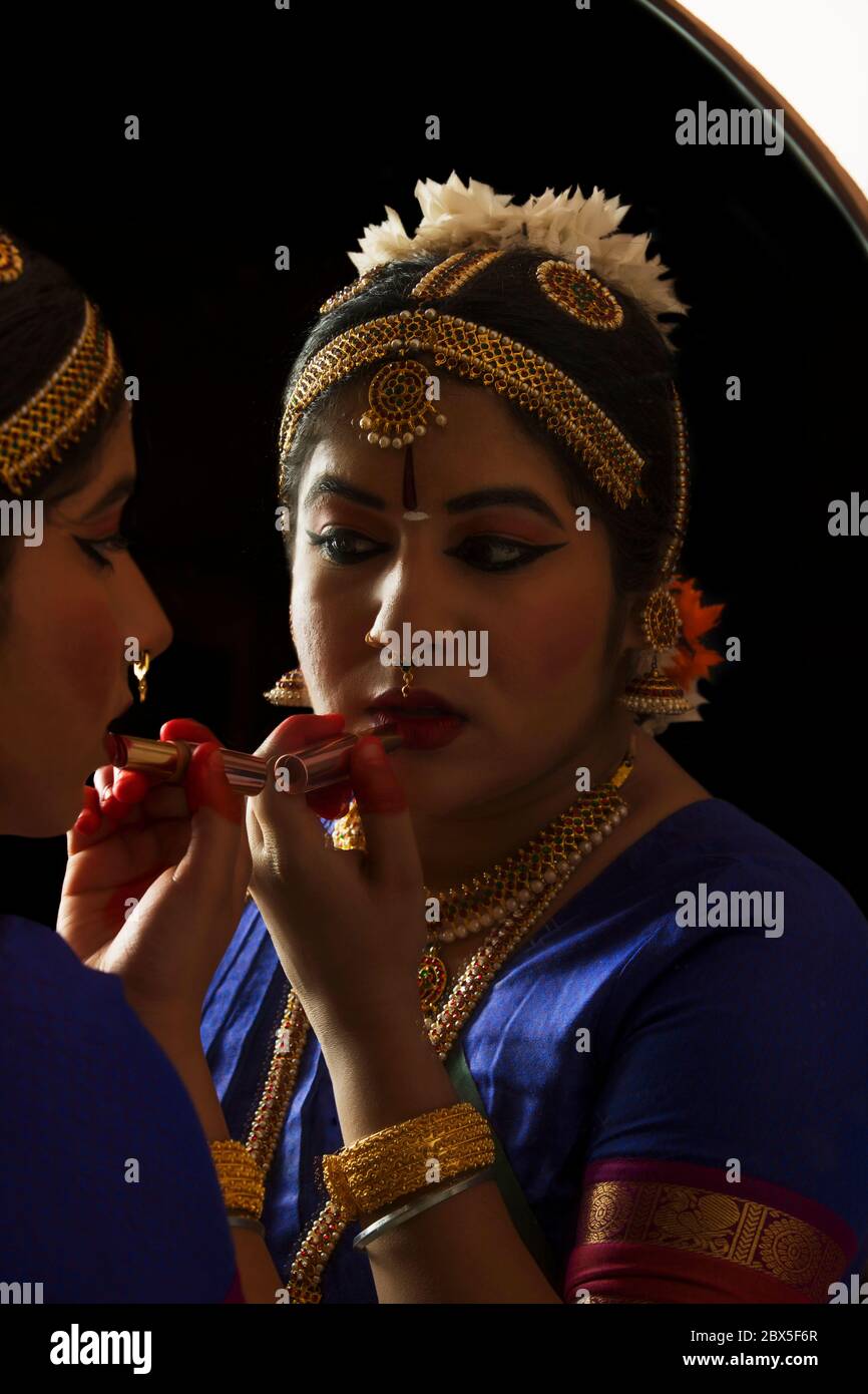 Ballerina Bharatnatyam che si guarda nello specchio e applica il rossetto sulle labbra. Foto Stock