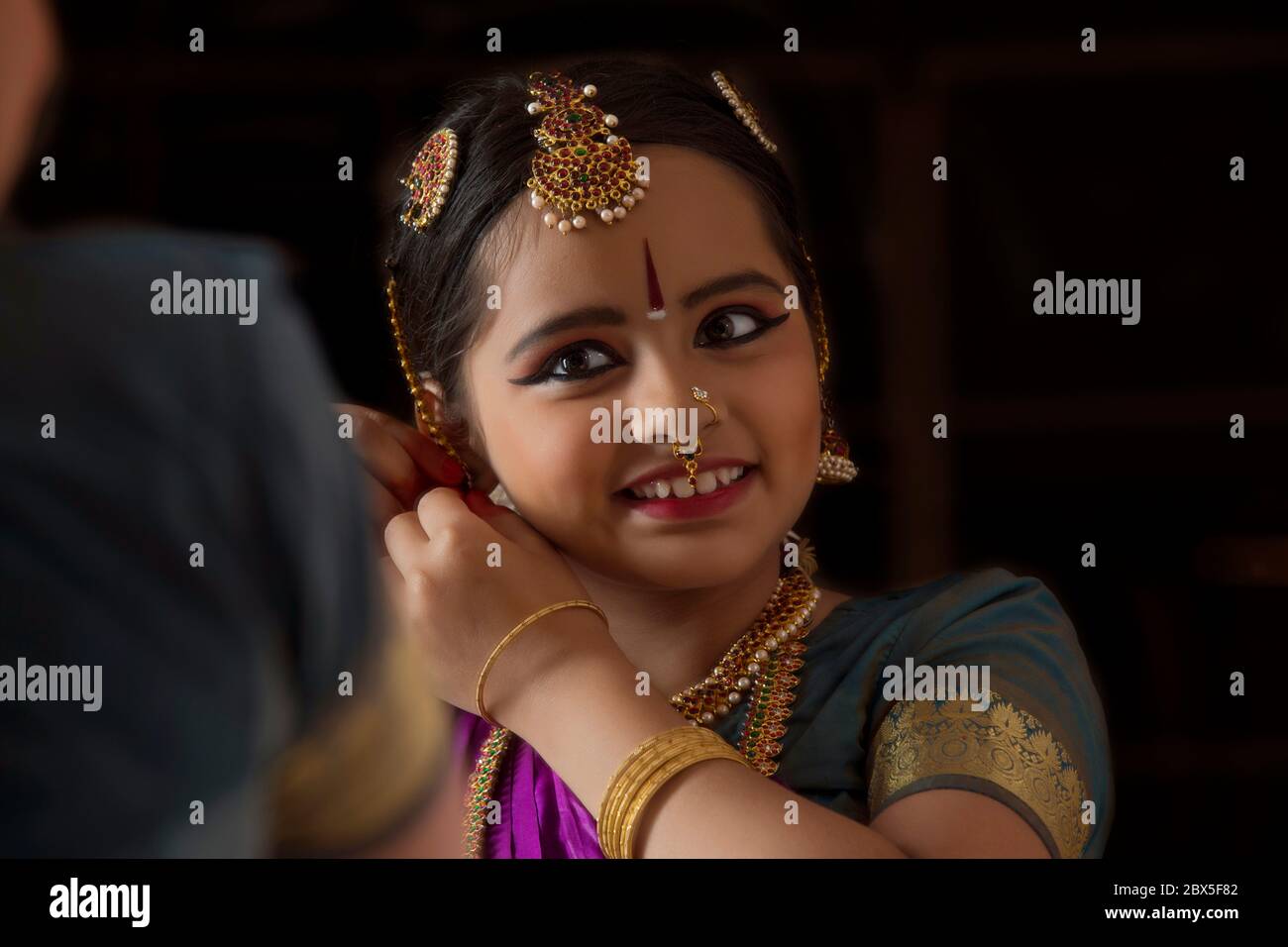 Giovane ballerina bharatnatyam che si guarda nello specchio mentre si prepara. Foto Stock