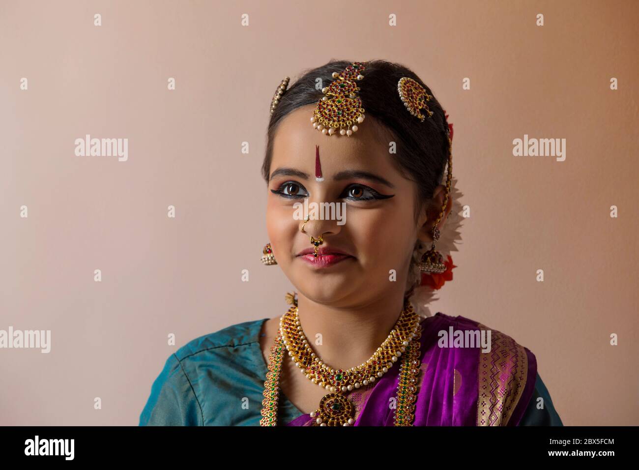 Giovane bharatnatyam ballerino in piedi davanti ad uno sfondo piano e sorridente. Foto Stock